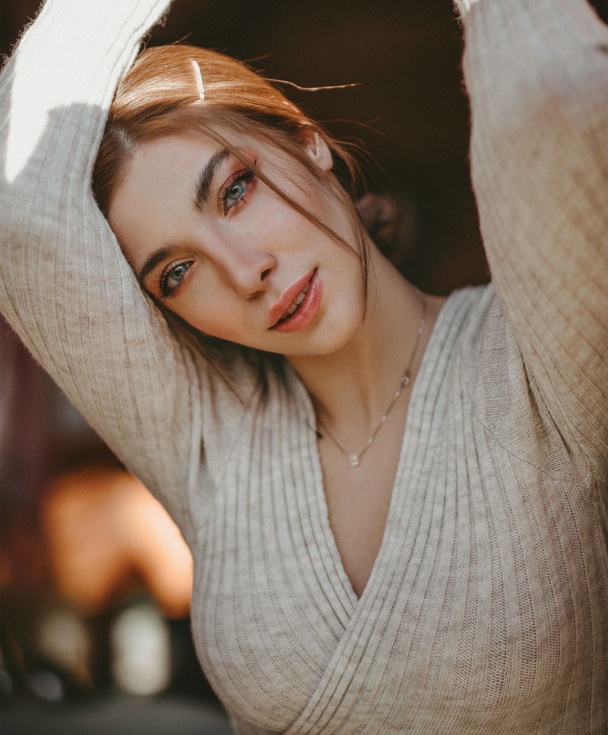 Model posing by window in neutral attire.