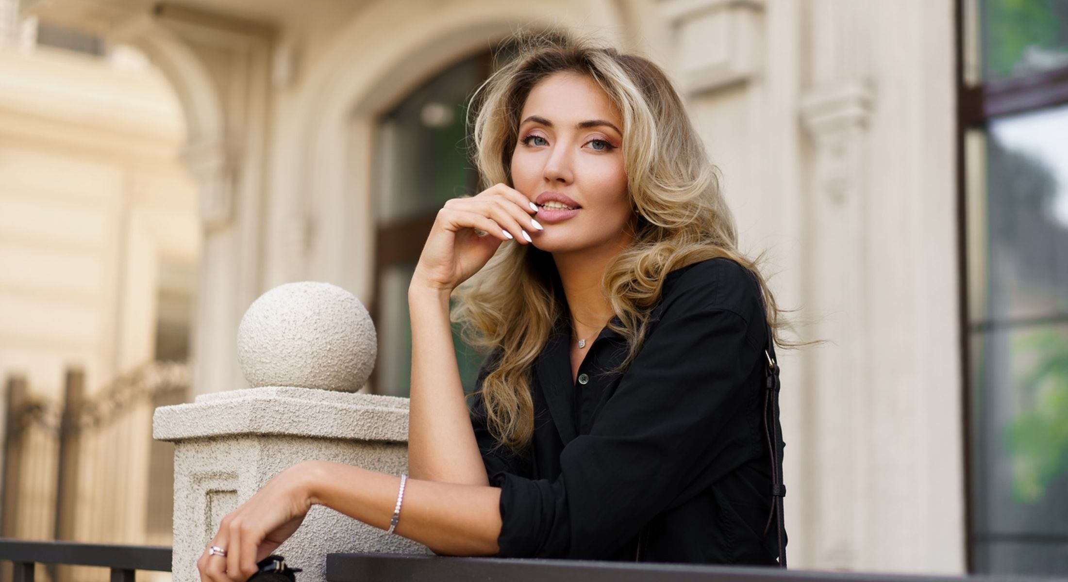 Smiling woman leaning on a stone fence.